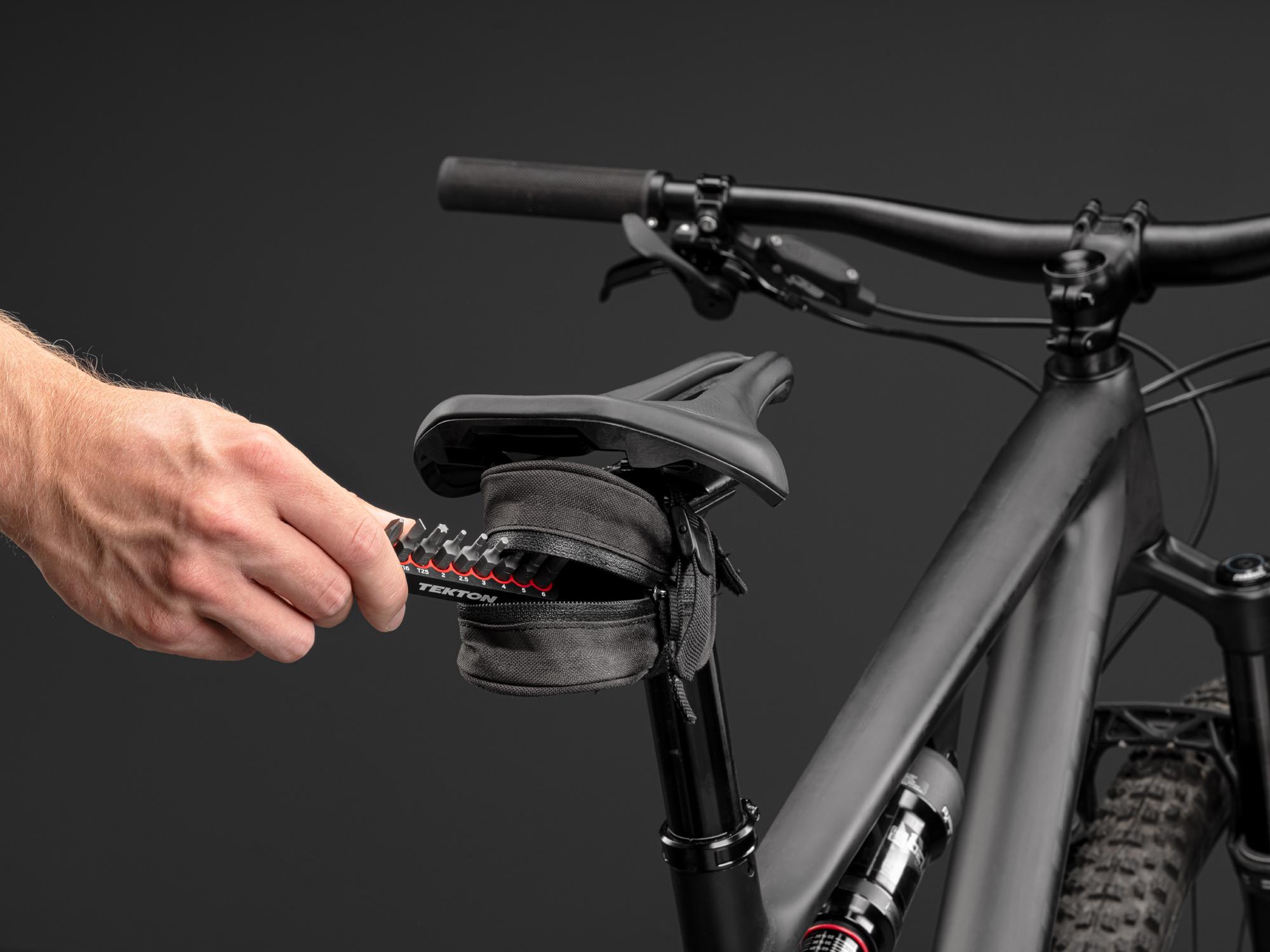 Someone placing a Tekton rail bit set in a bicycle seat pouch. Item #DZZ93003.