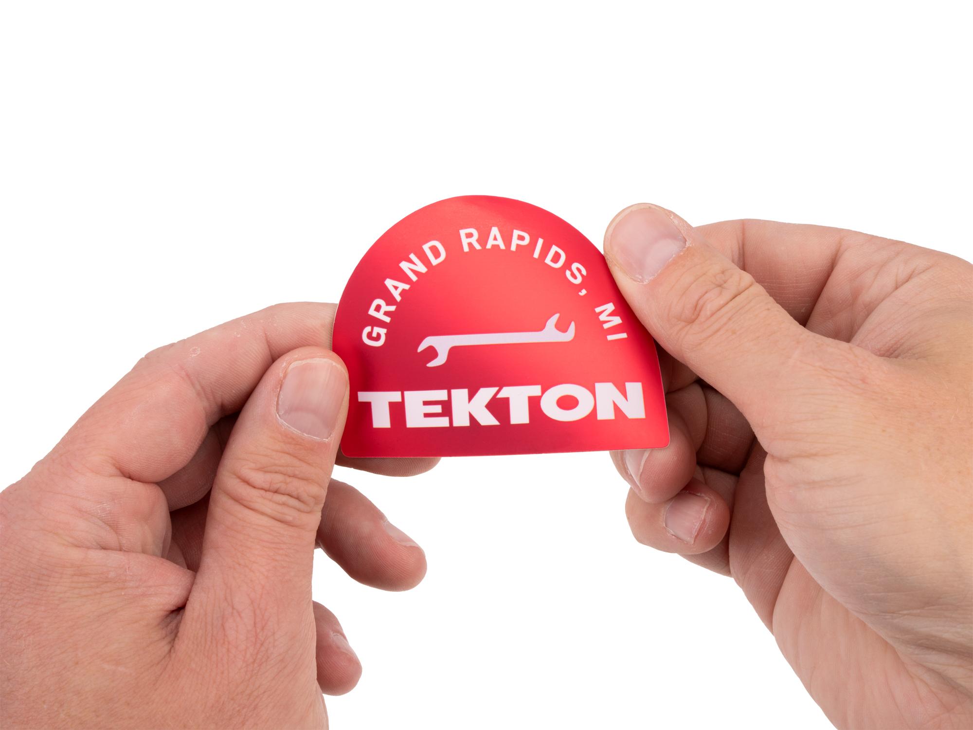 Person holding red Tekton sticker. Item #APG51008