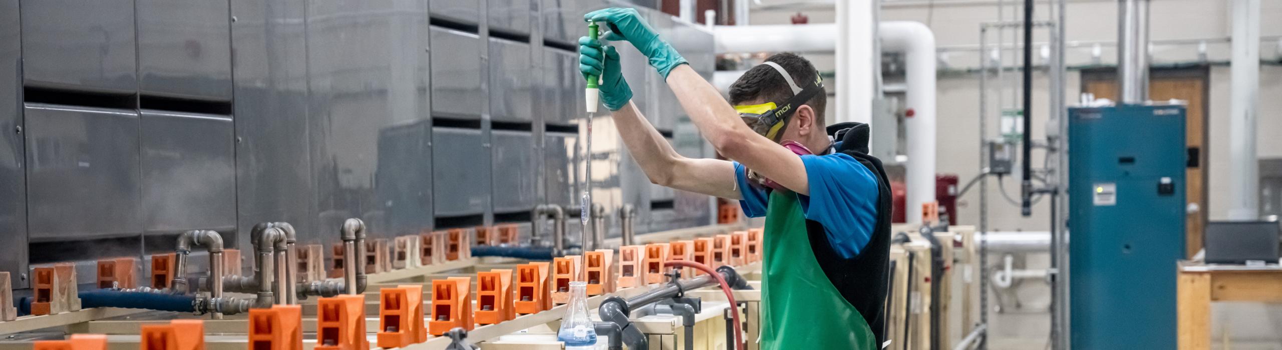 A technician takes a sample of a metal plating solution.