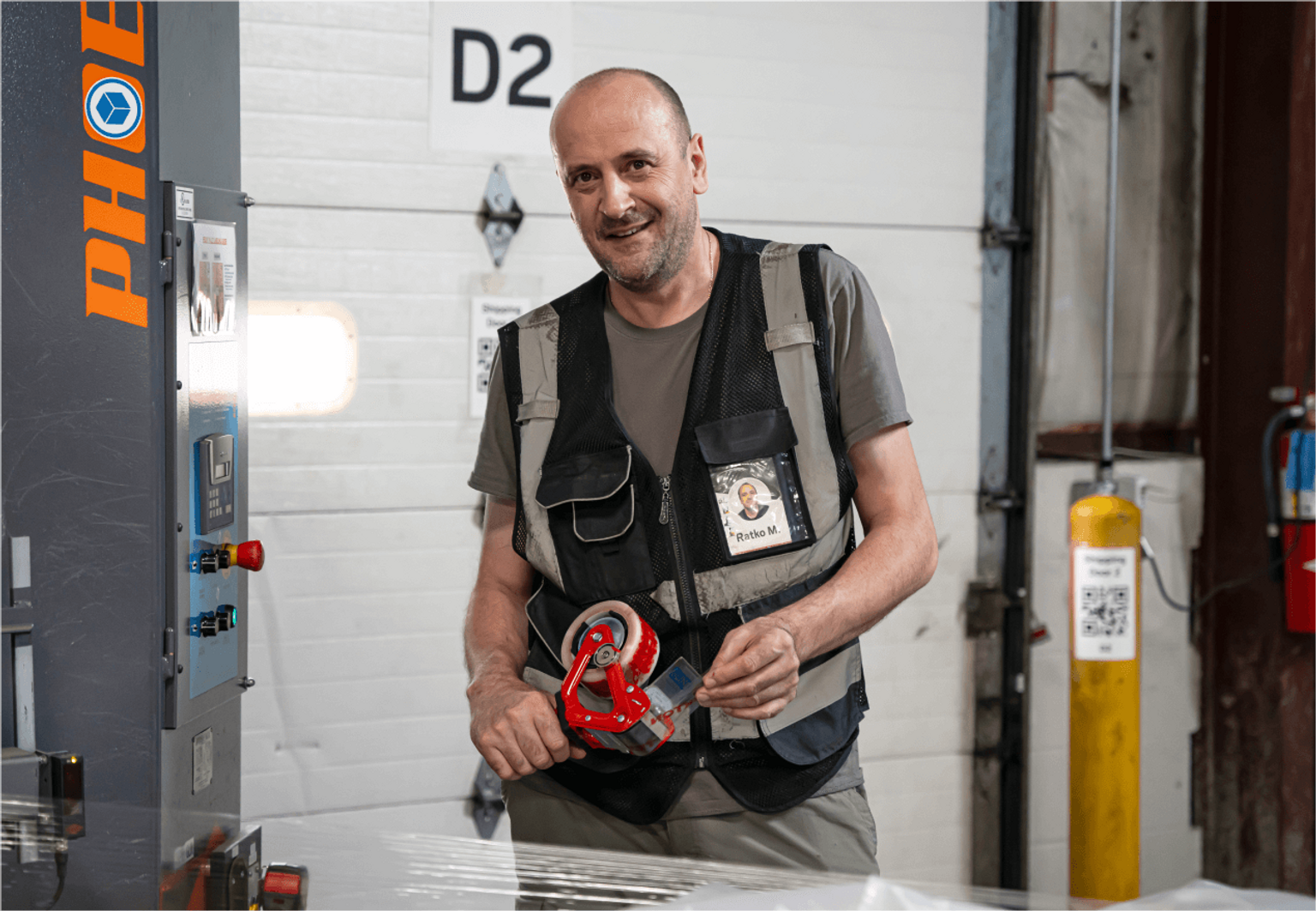 A person in a vest taping a shipping box for delivery.