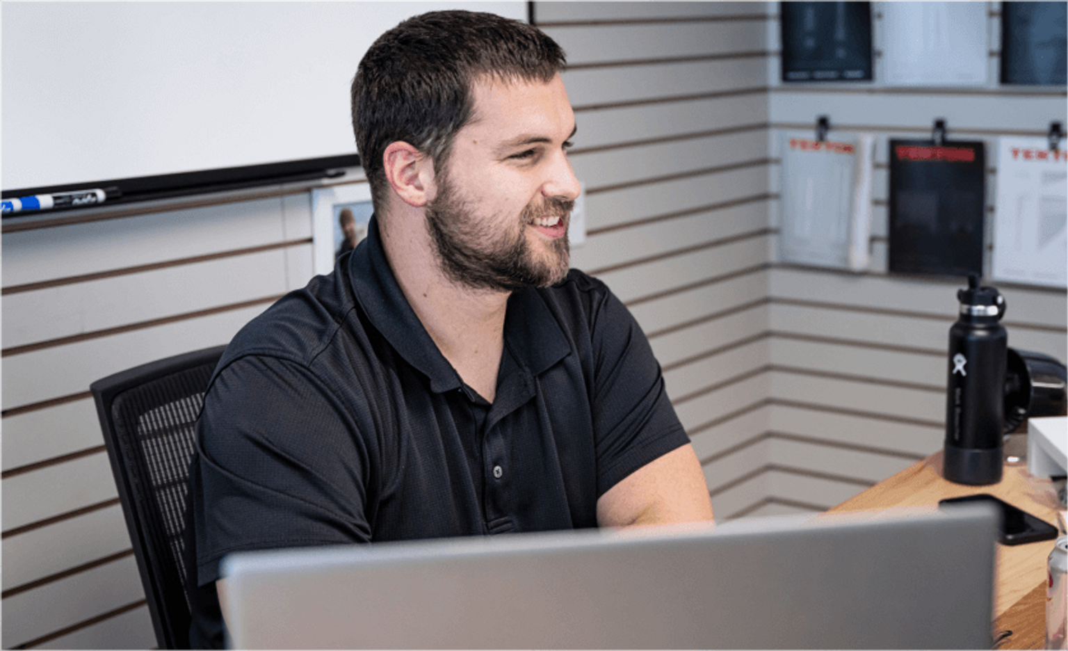 A person smiling and working on a computer screen.