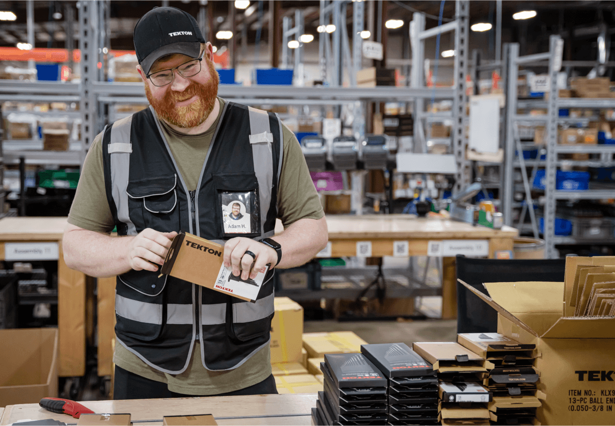 Fulfillment specialist packing tools in shipping boxes in a warehouse.