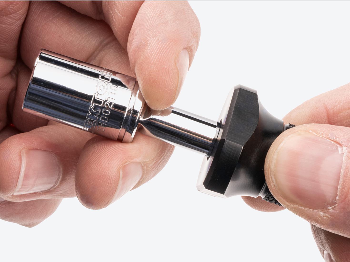 A hand removing a socket from the shank of a spinner handle