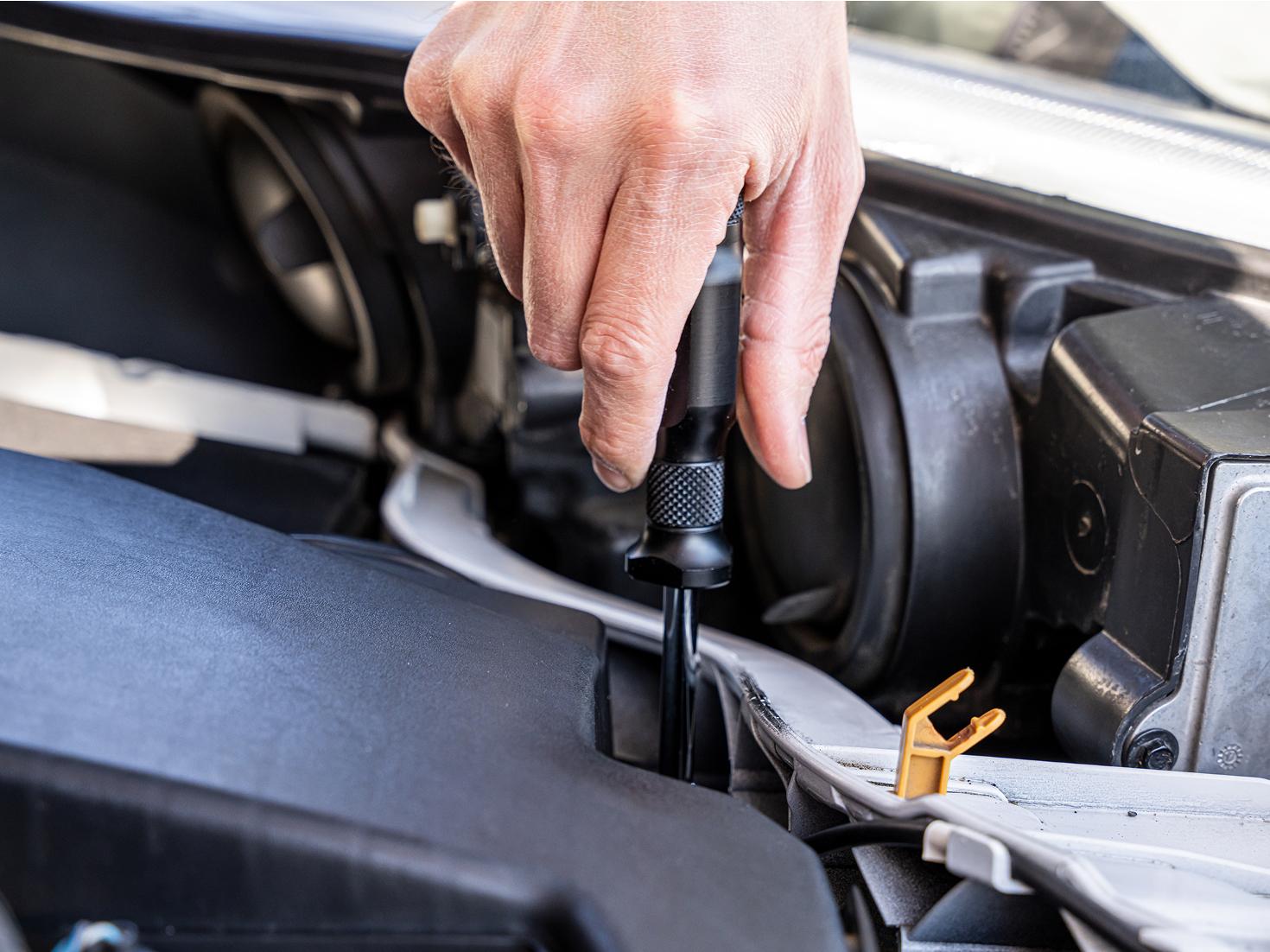 A spinner handle being used in the engine bay of a vehicle