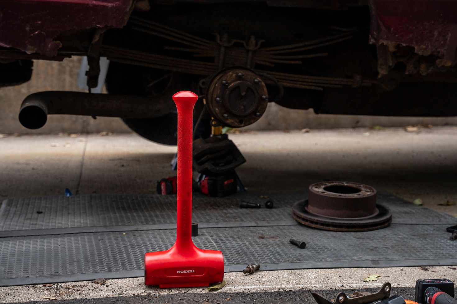 A hammer standing on its head with a raised vehicle in the background.