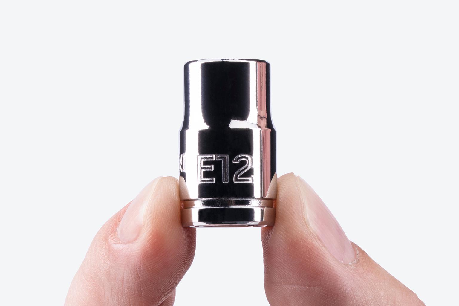 A Tekton 3/8 Inch Drive x E12 External Star Socket being held, showing the large stamped "E12" markings.