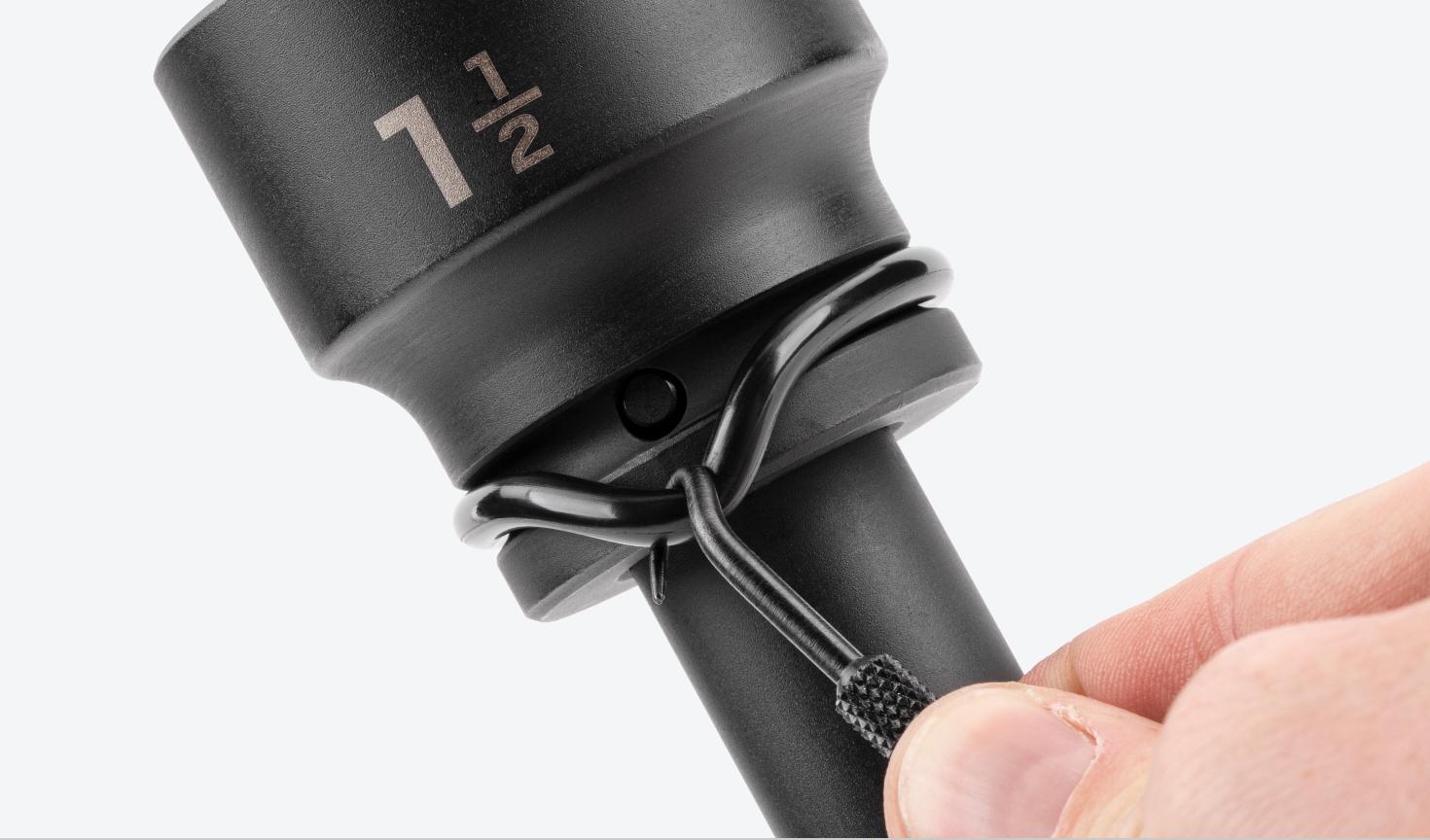 A hand holding the Socket Retaining Pin and Ring Removal Tool is hooking a retaining ring off of a Tekton impact socket.