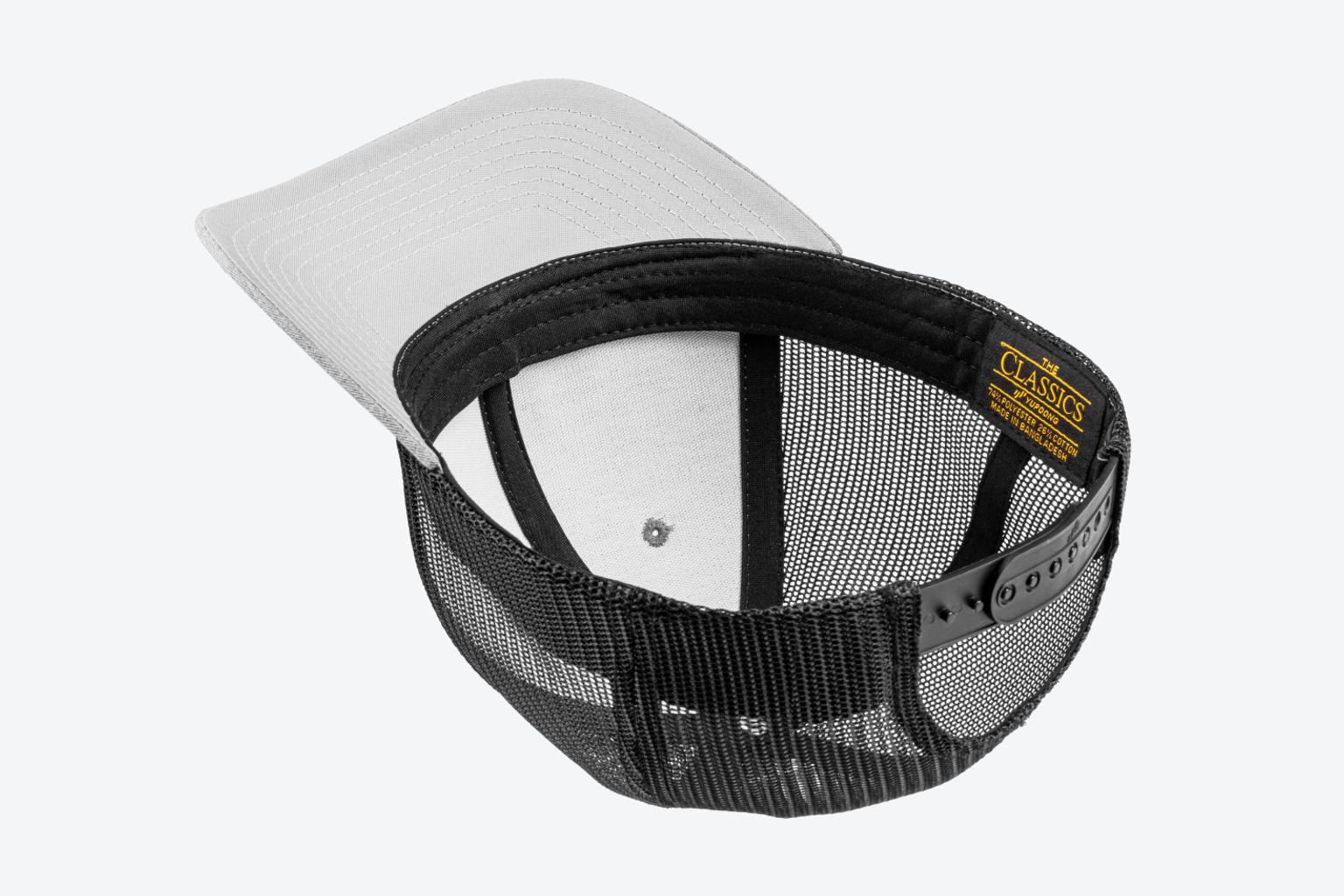 A gray low profile Tekton hat is upside down on a light gray surface, showing the structured design.