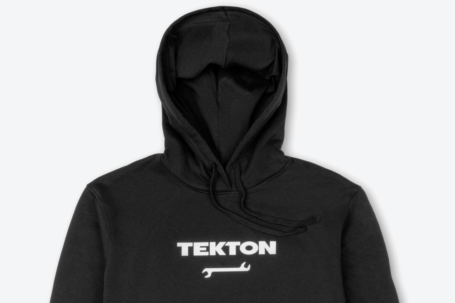 A black heavyweight Tekton hoodie laying out on a light gray surface.