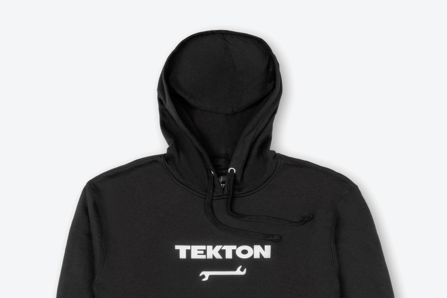 A black midweight Tekton hoodie laying out on a light gray surface.