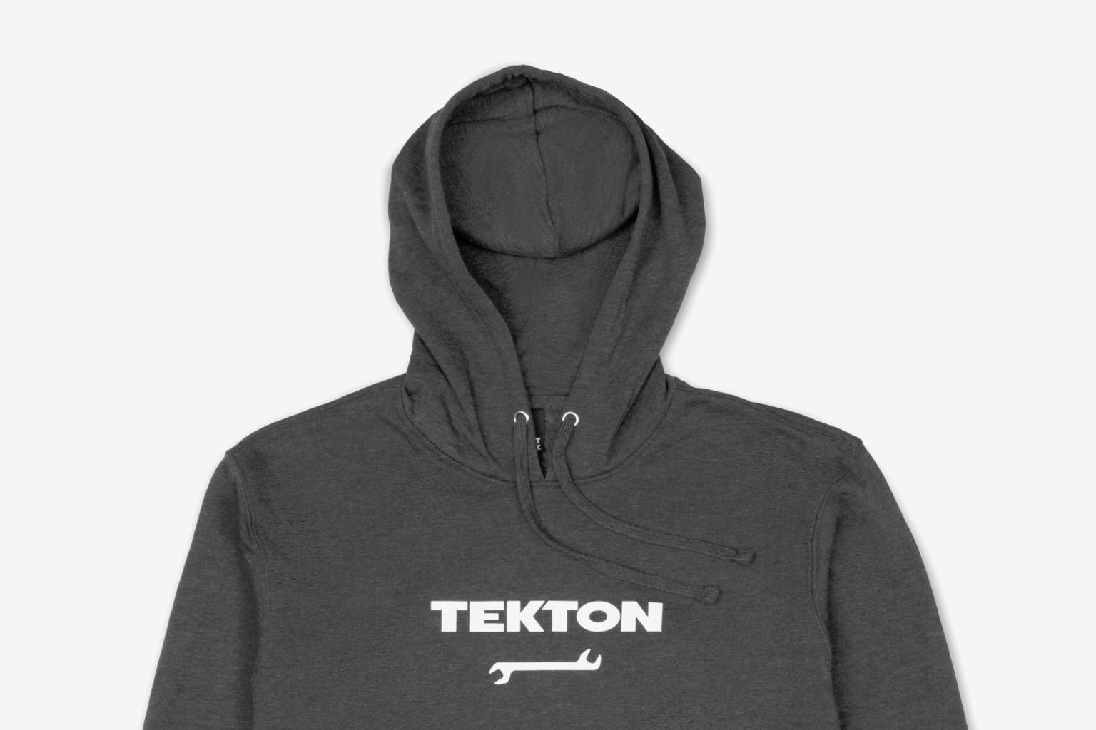 A dark heather gray midweight Tekton hoodie laying out on a light gray surface.