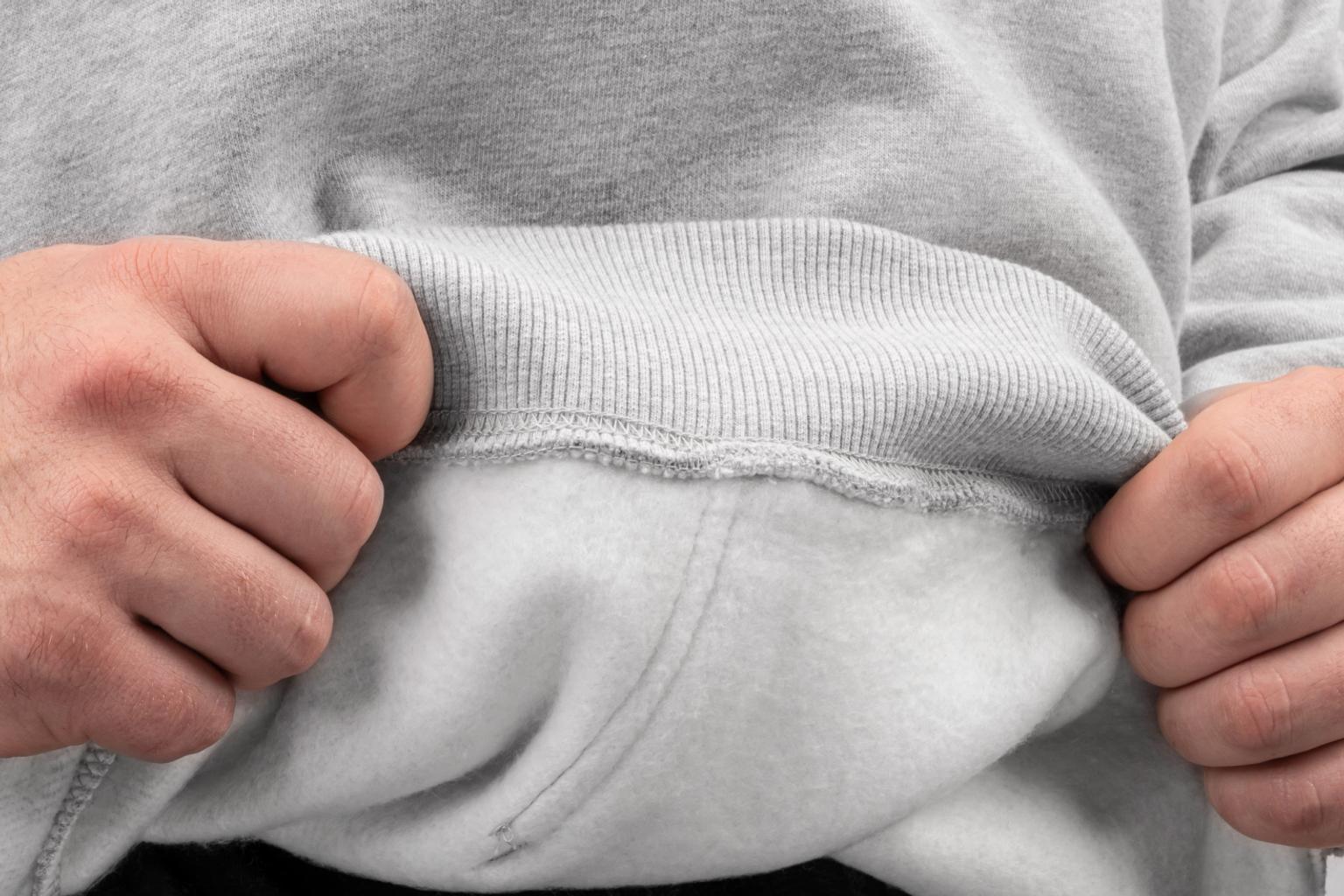 A person wearing a light gray hoodie showing the soft fleece lining on the inside of the hoodie.