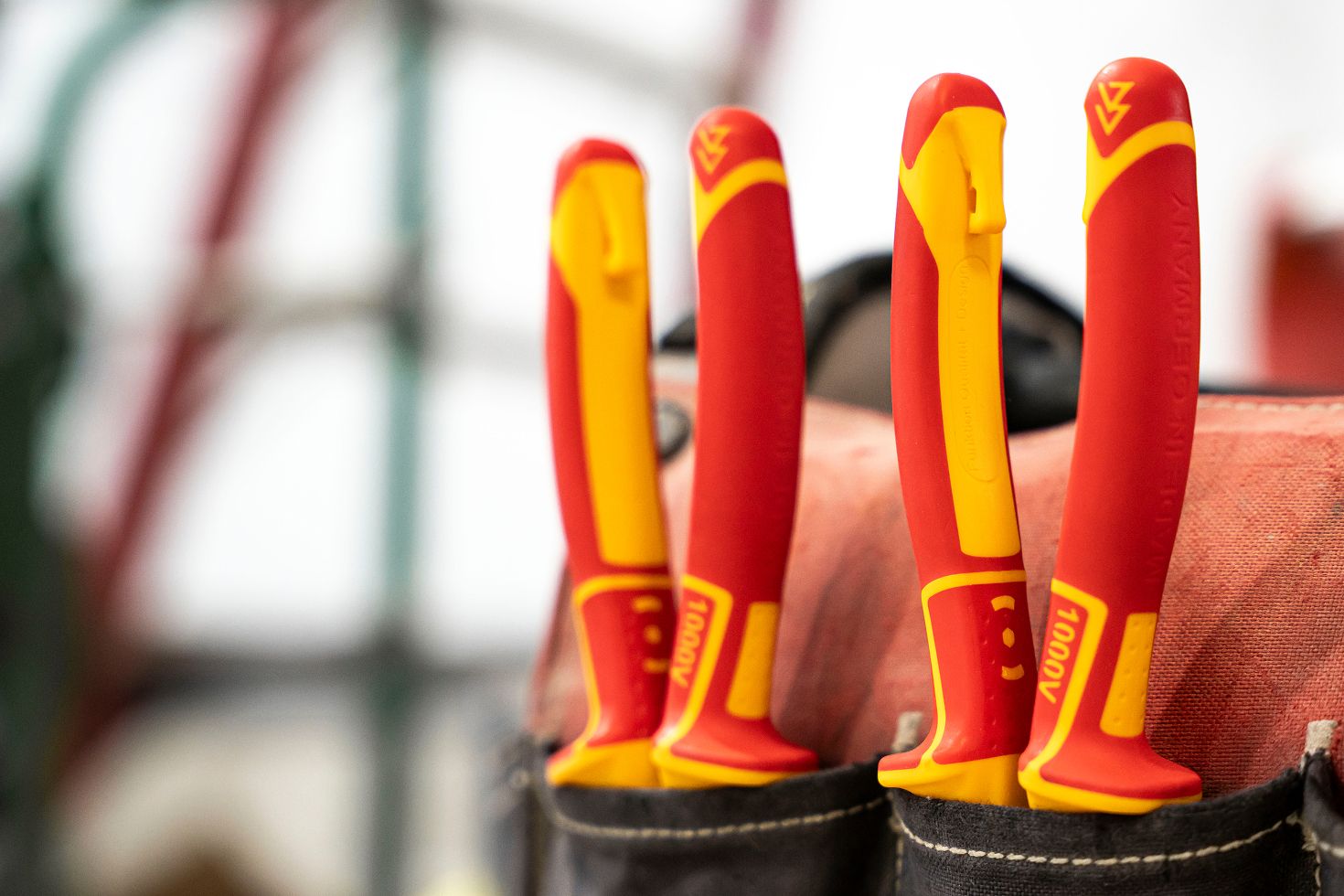Two insulated pliers in the pockets of a work bag.