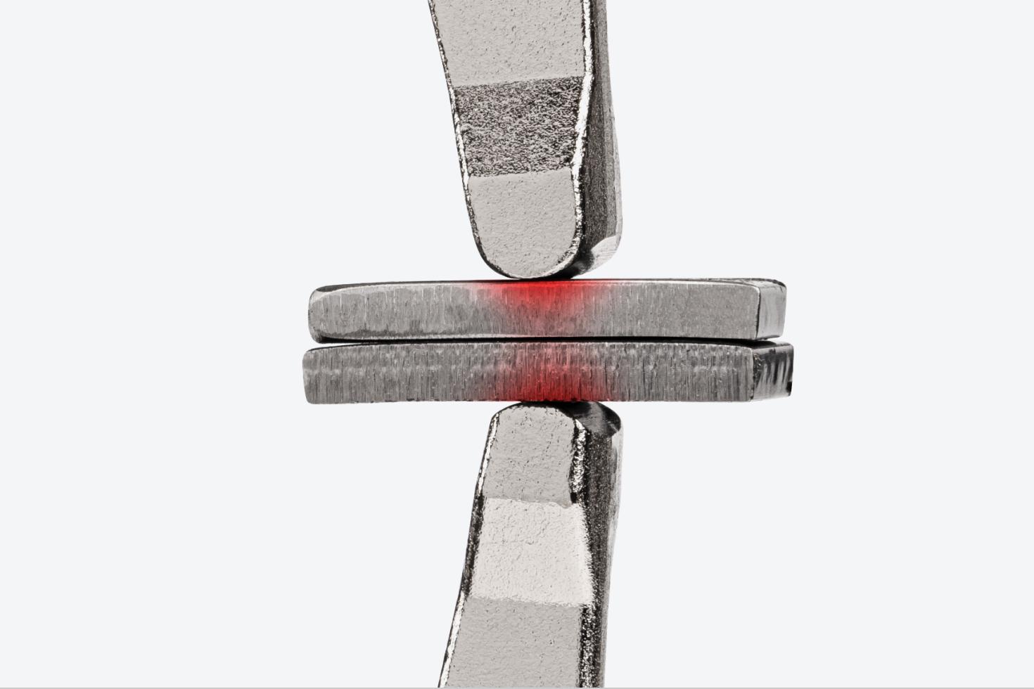 Fixed ends of a locking C-clamp clamping down on two pieces of metal. There is a red texture on the pieces of metal, showing the concentrated clamping point.