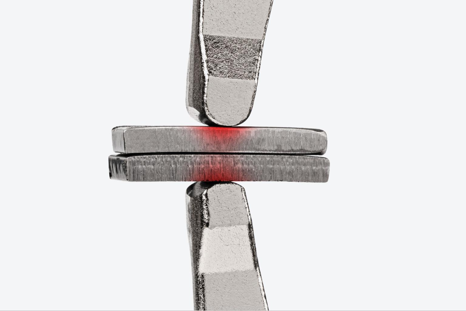 Fixed ends of a locking C-clamp clamping down on two pieces of metal. There is a red texture on the pieces of metal, showing the concentrated clamping point.