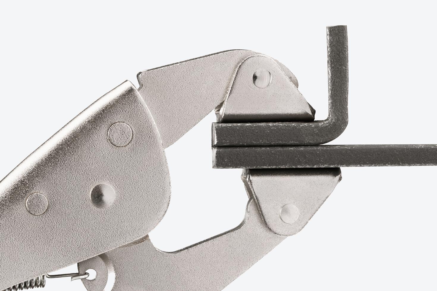 A clamp clamping down on two pieces of steel.
