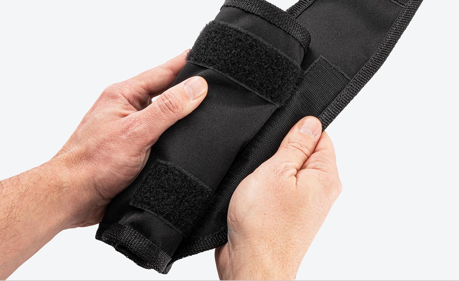 Two hands opening a pouch, clearly showing the hook-and-loop style fastener.