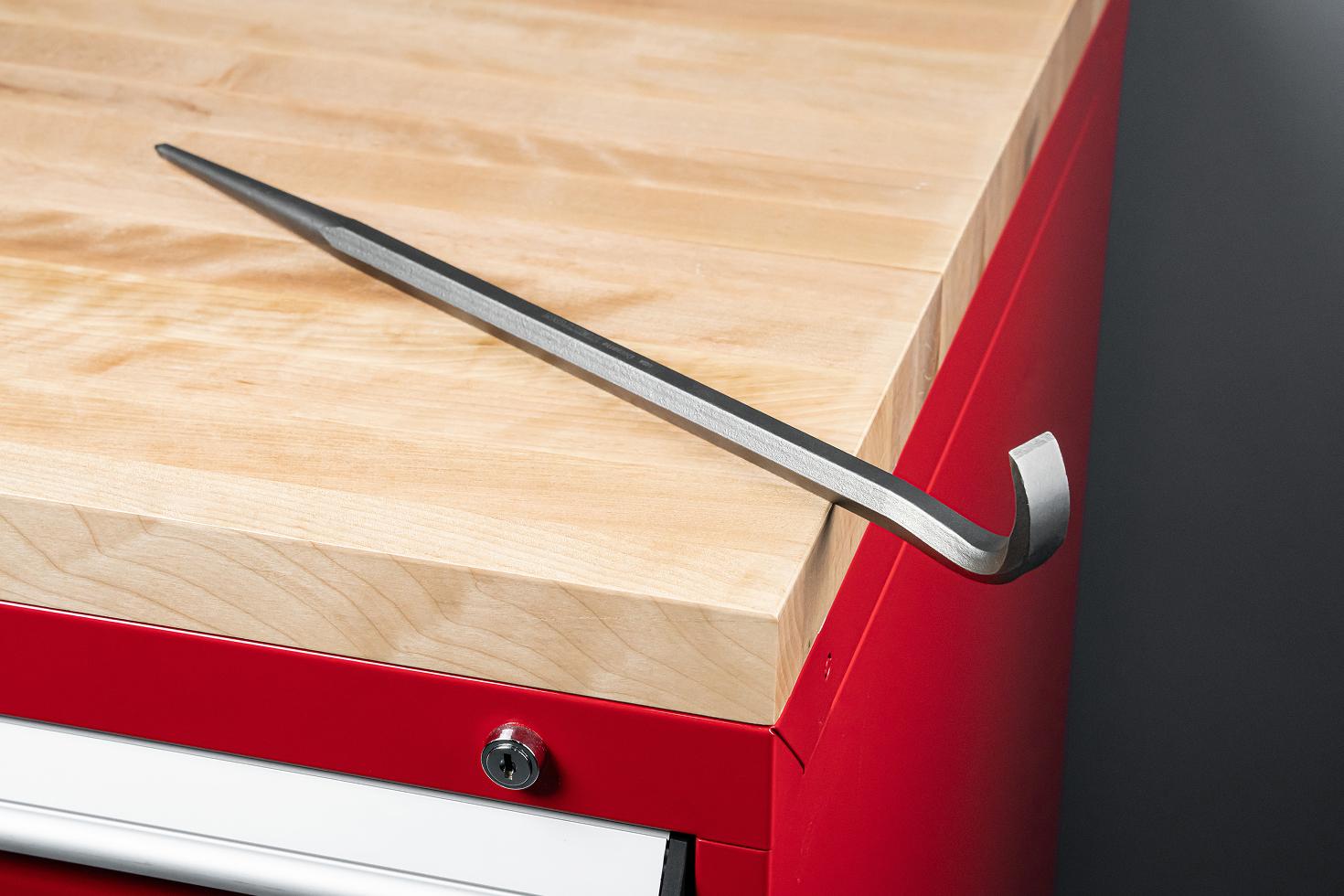 A rolling head alignment pry bar sitting on top of a red tool cabinet with wood block top.
