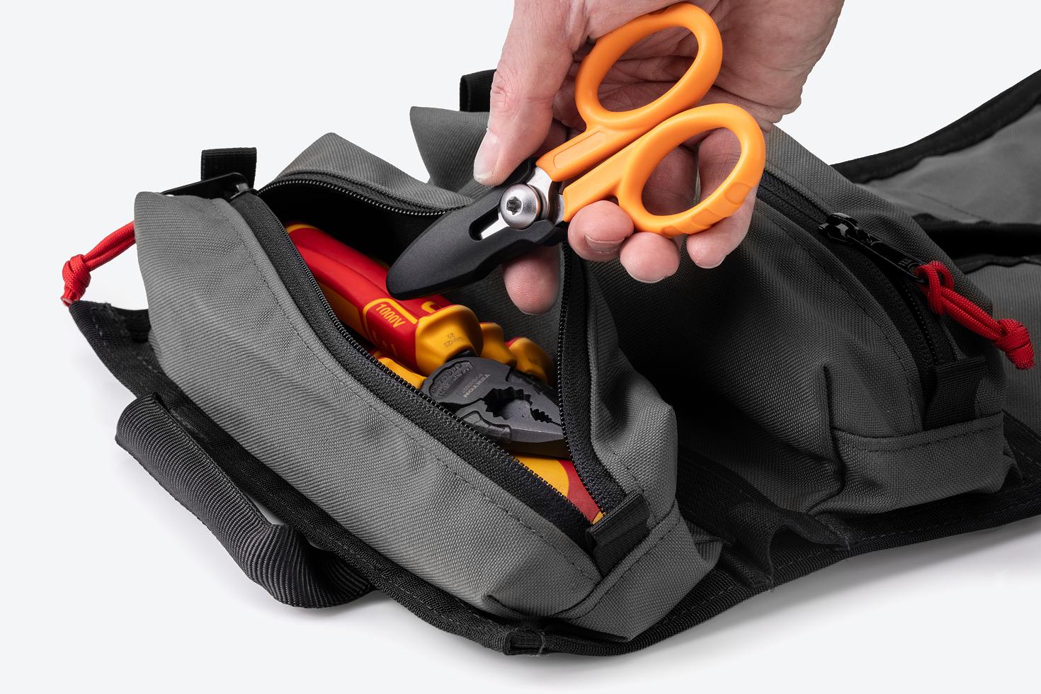 A hand pulling scissors out of the pouch of an MTR tool roll