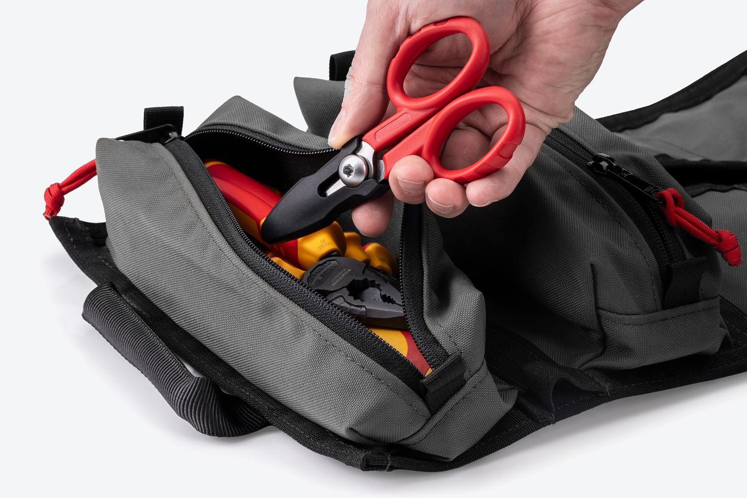 A hand pulling scissors out of the pouch of an MTR tool roll