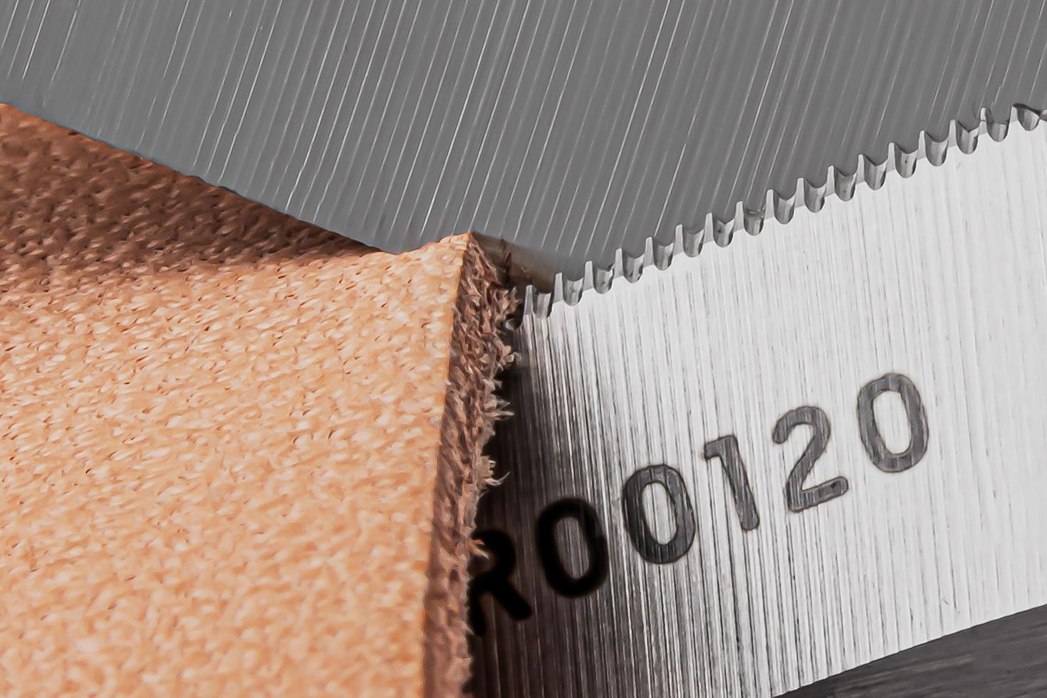 Close-up image of the micro-serrations on the blade of the scissors cutting a piece of leather