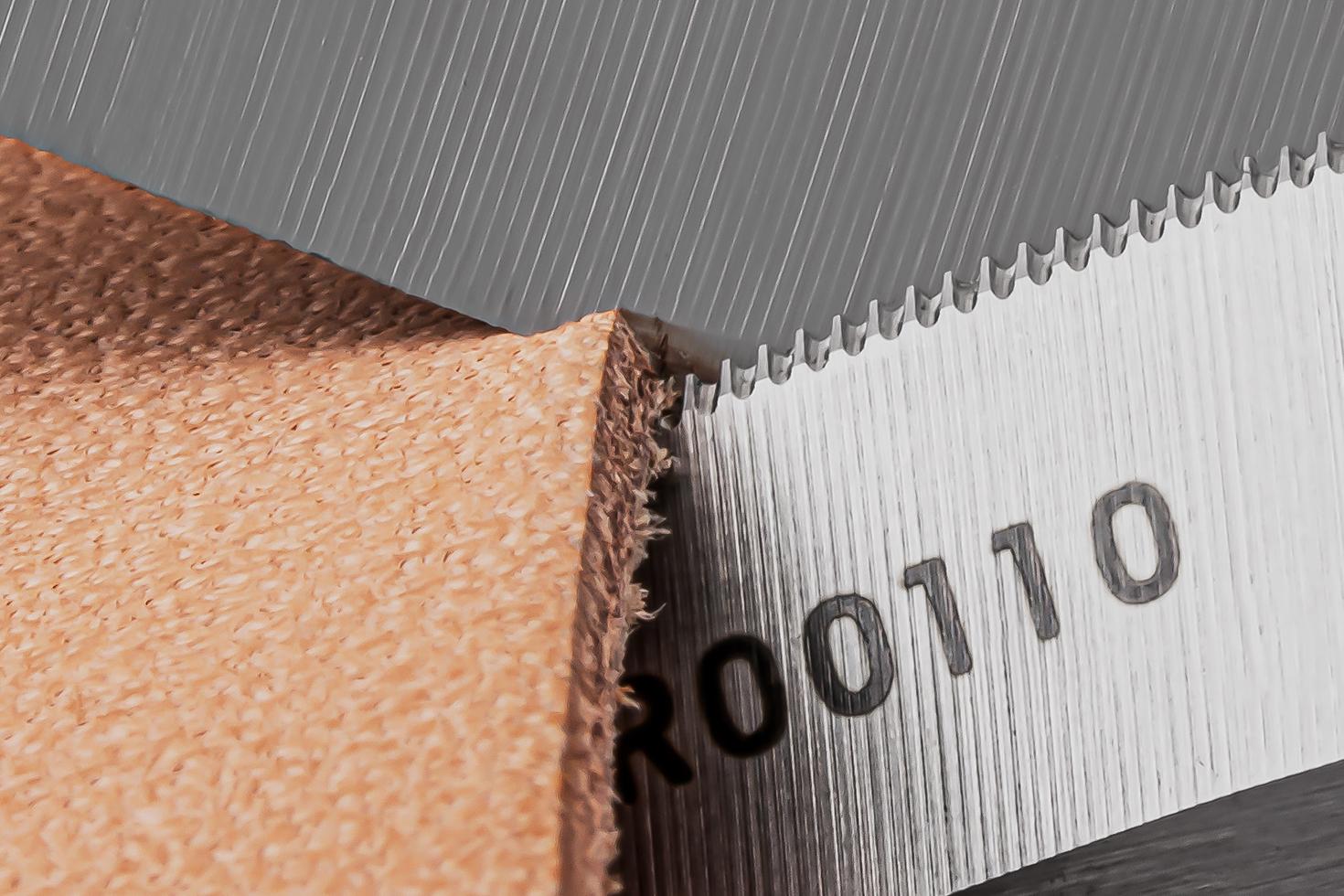 Close-up image of the micro-serrations on the blade of the scissors cutting a piece of leather