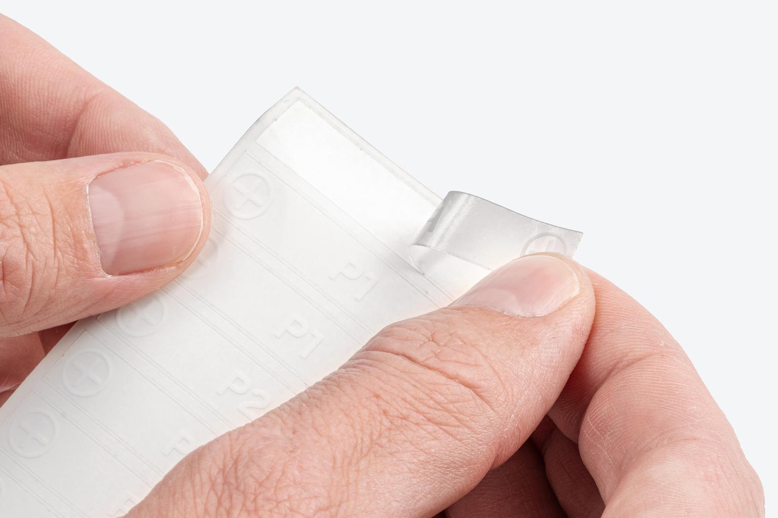 A hand pulling a label off the backer sheet.