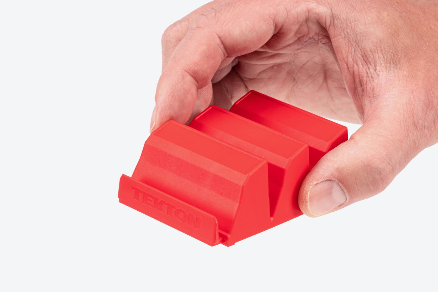 A hand holding a red large modular driver organizer piece.