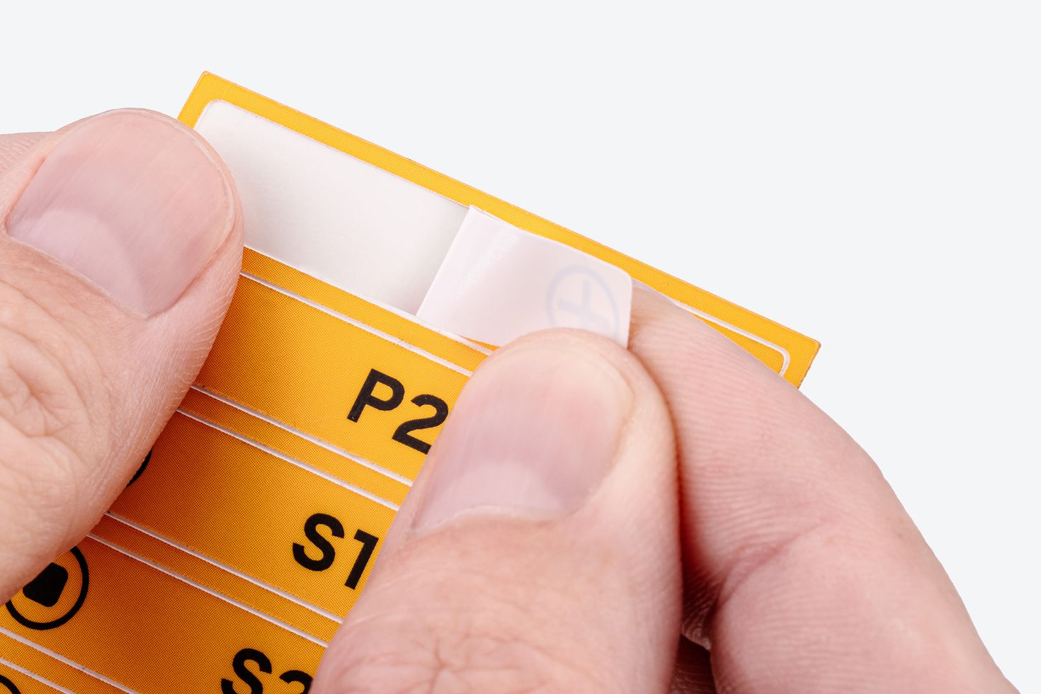 A hand pulling a label off the backer sheet.