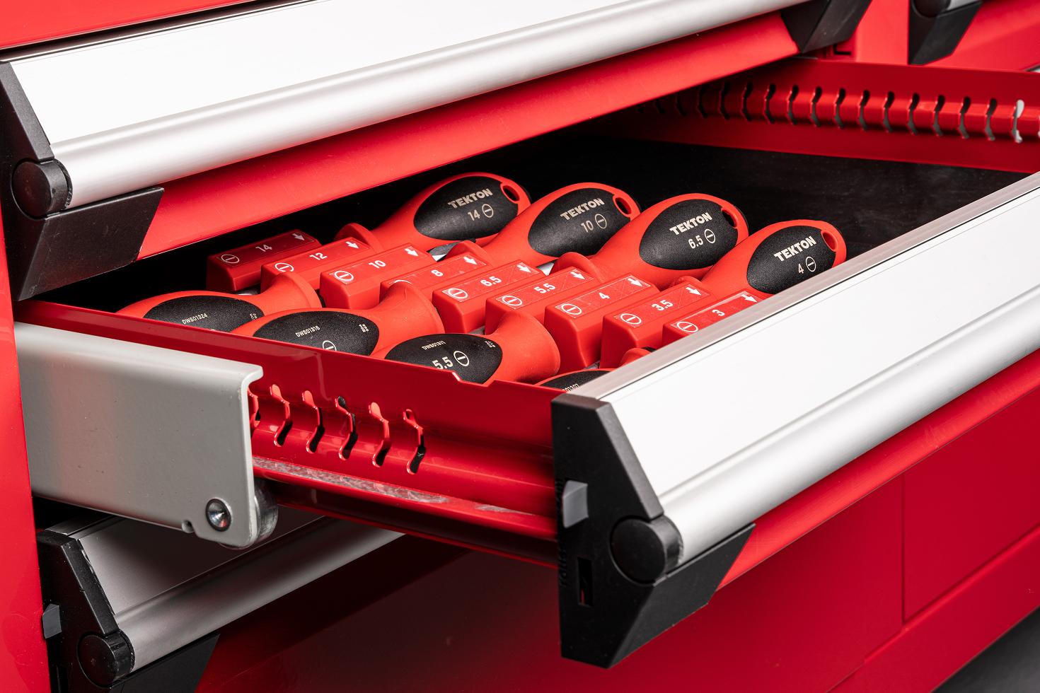 Tekton screwdrivers in red modular driver organizers in a shallow drawer of a red tool cabinet.