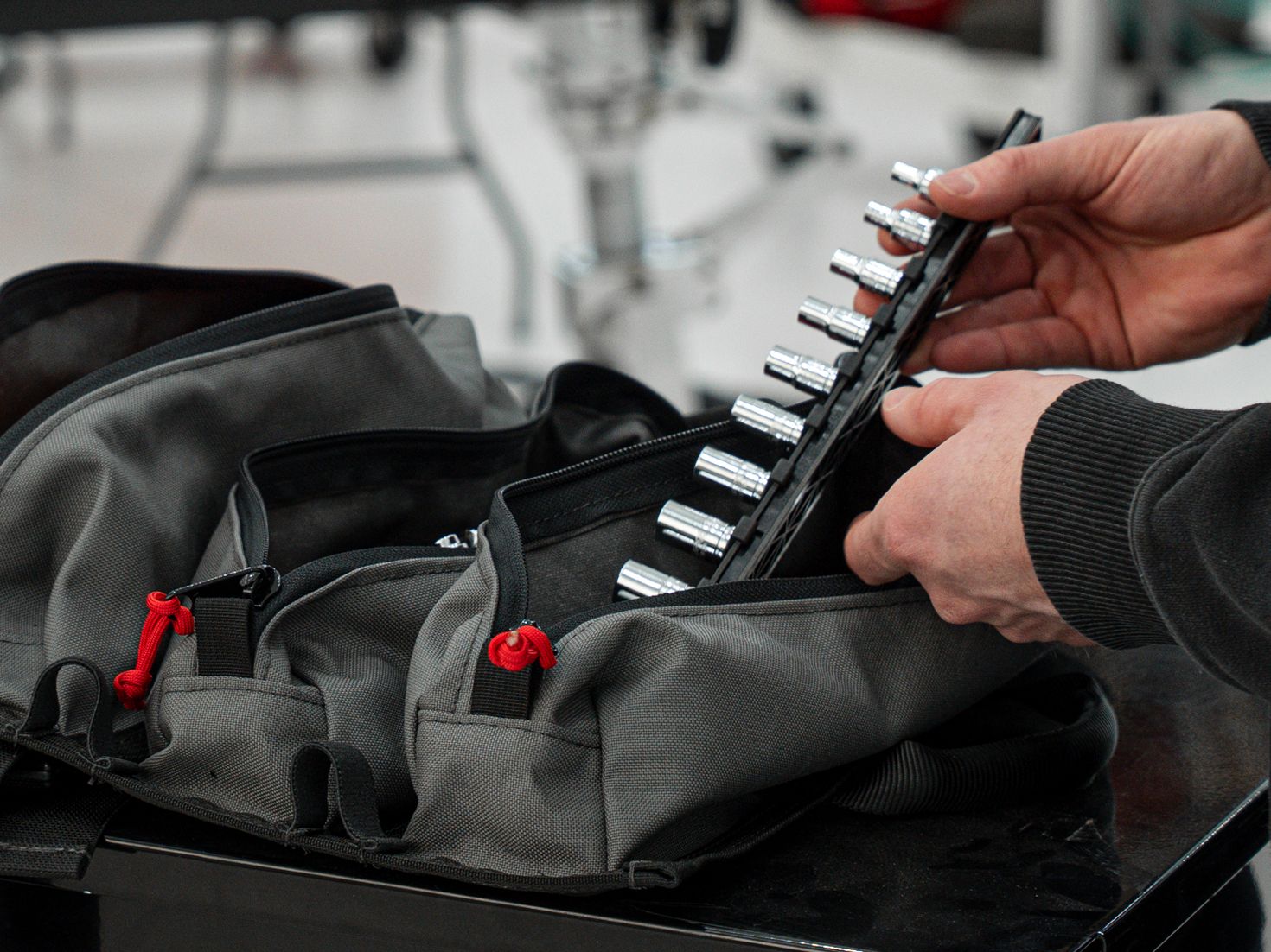 A hand pulling a rail with hand drive sockets out of a zippered pouch