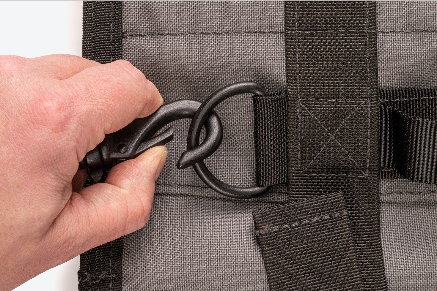 A hand opening the metal swivel snap hook