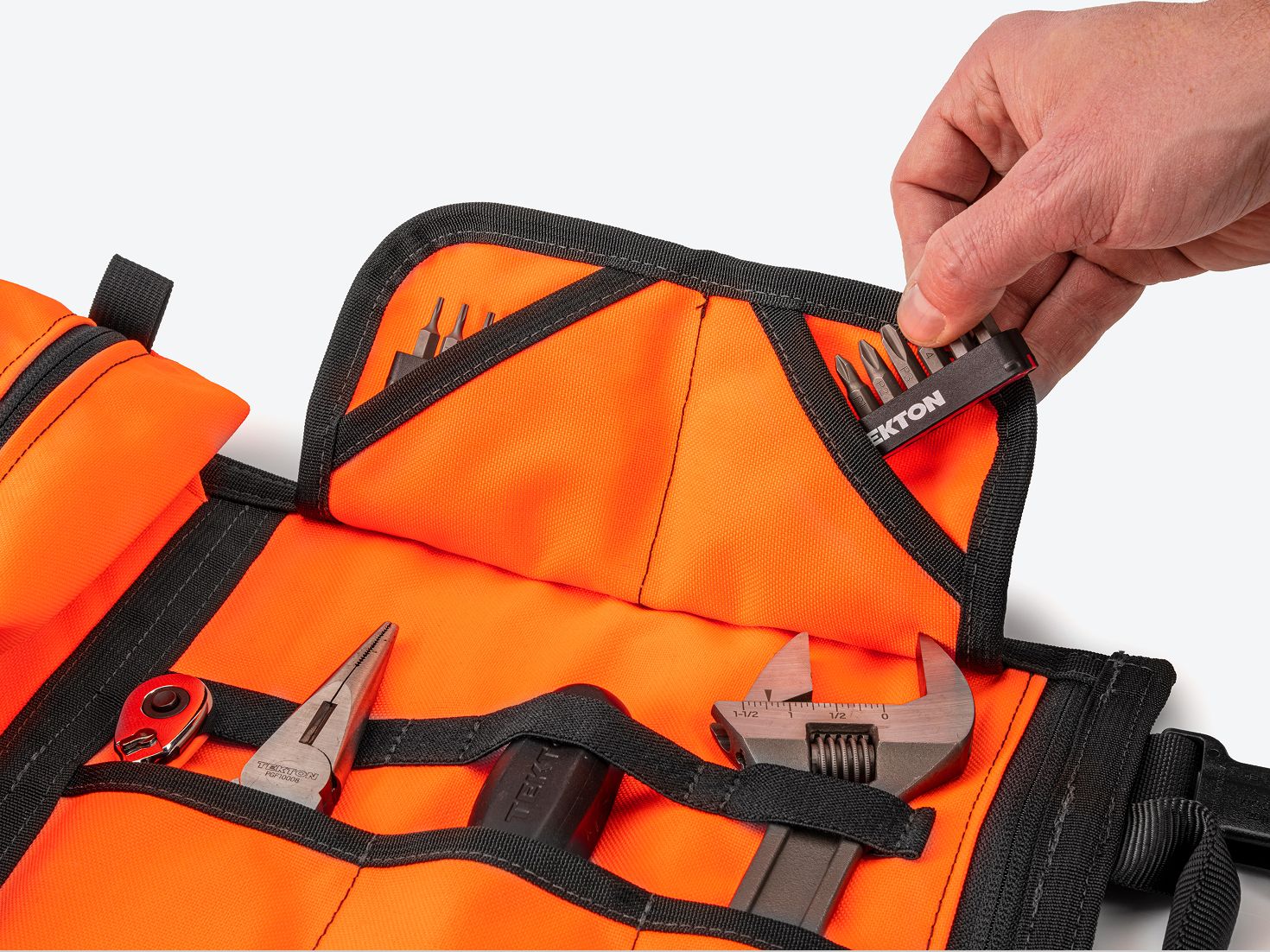 A hand pulling a bit rail out of the flap pocket of an orange MTR2 Mini