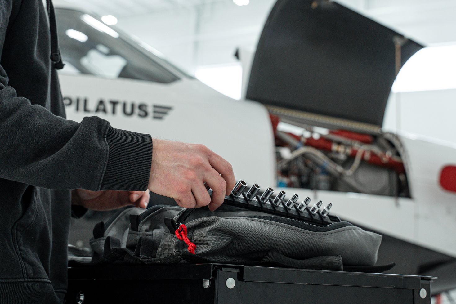 A person taking a socket rail out of a gray MTR with an airplane in the background