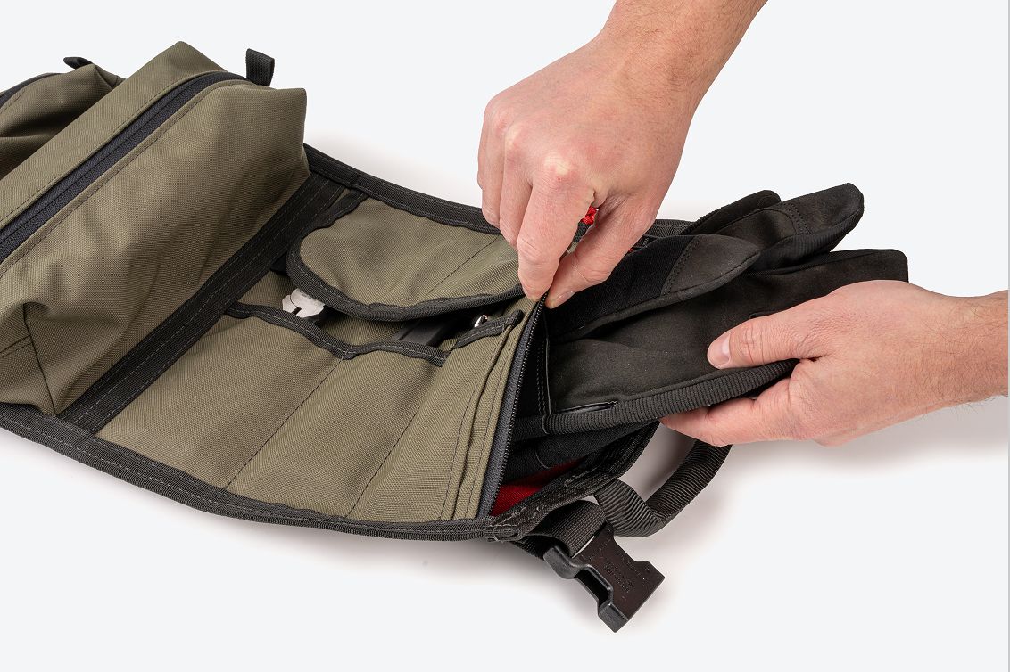 A person taking gloves out of the zipper pocket on a green MTR