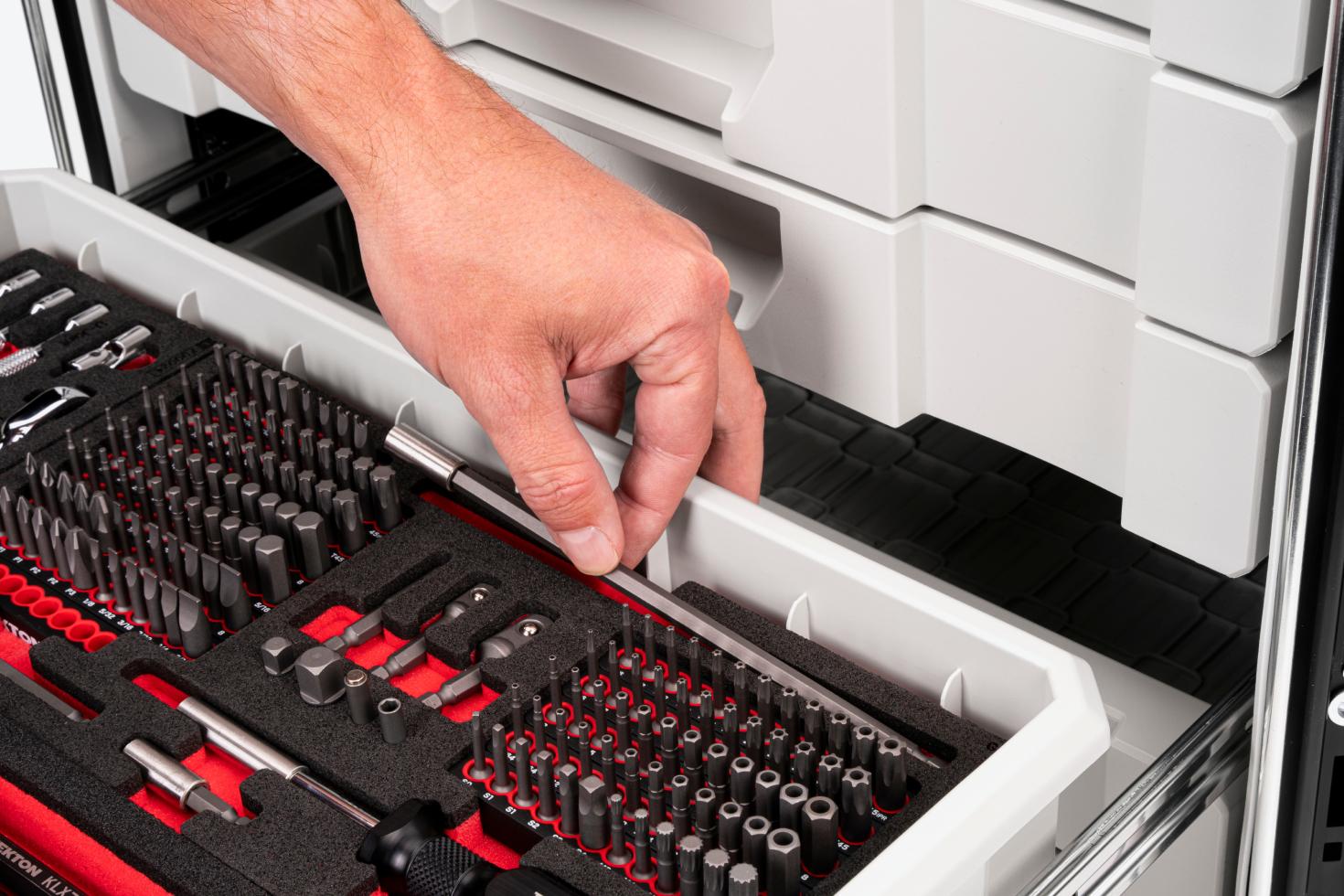 A hand pulling a bit holder extension out of the back of a drawer