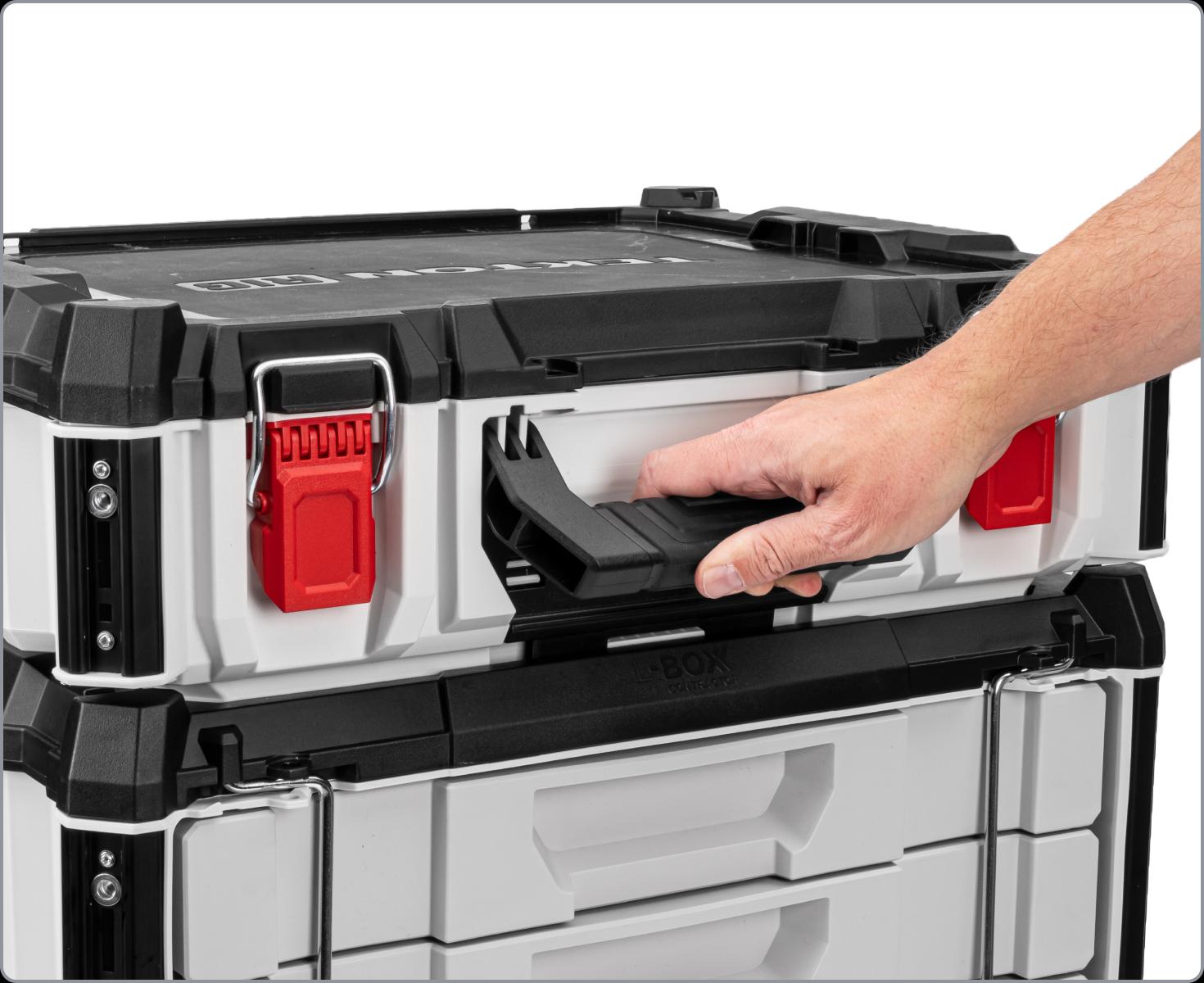 A hand lifting the handle of a tool box to disconnect it from a stack