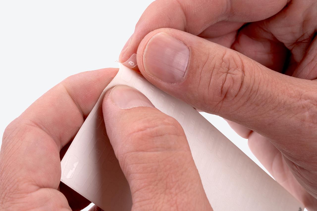 A hand pulling a label off the label sheet.