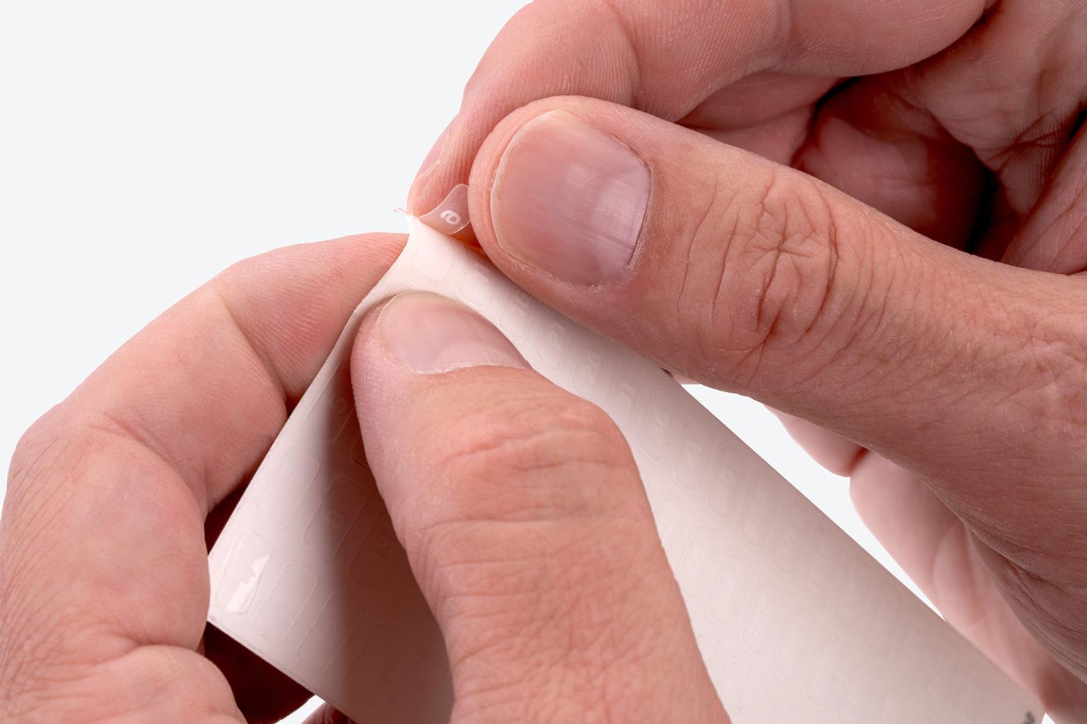 A hand pulling a label off the label sheet.