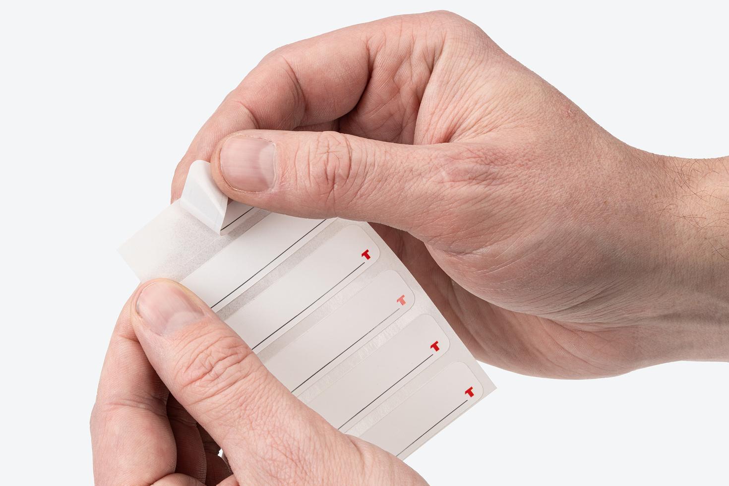 A hand pulling a label off the label sheet.