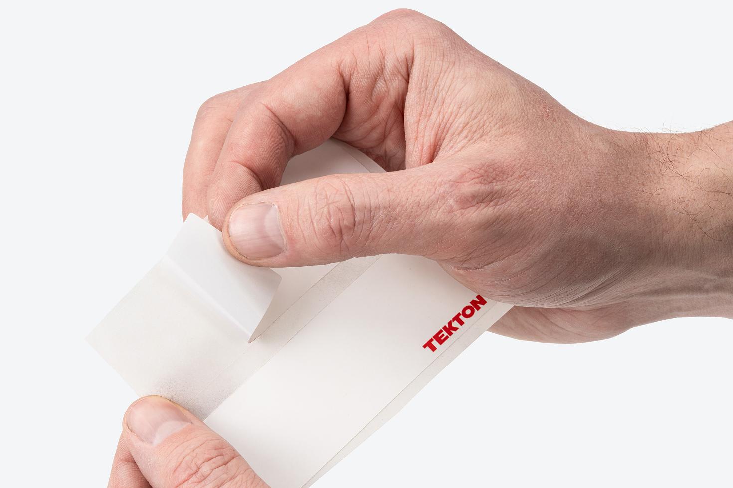 A hand pulling a label off the label sheet.