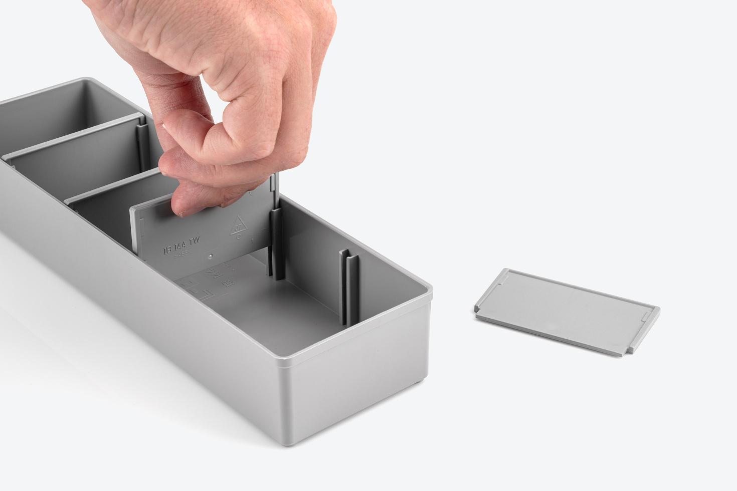 Hand removing divider from gray organizer bin.