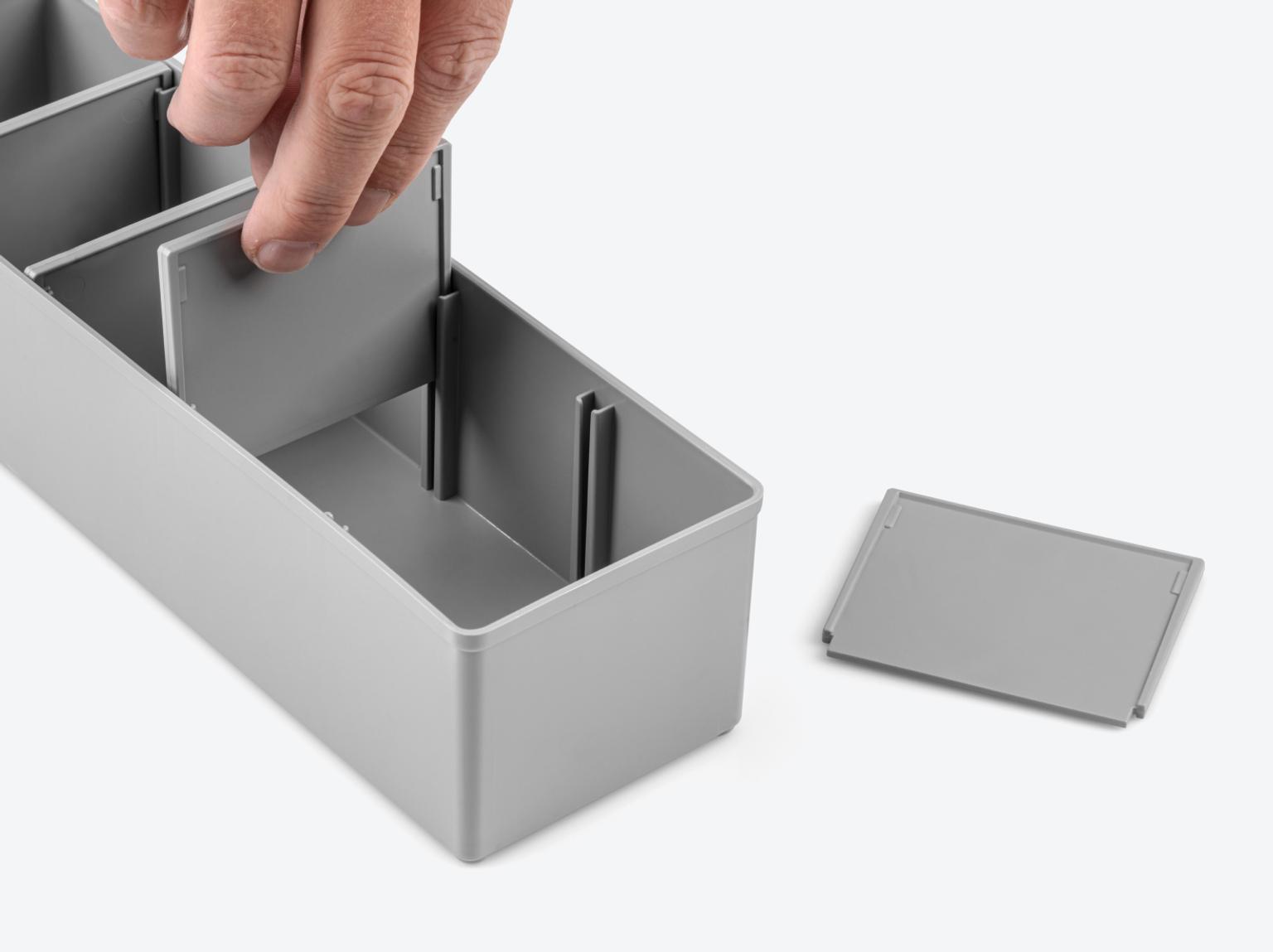 Hand removing divider from gray organizer bin