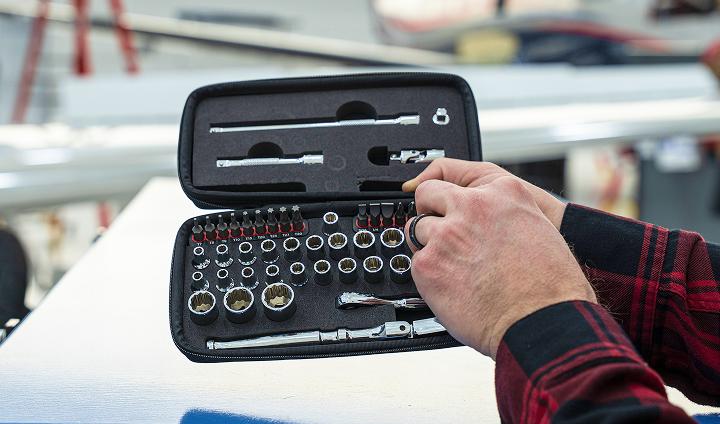 A person holding a black cased tool kit