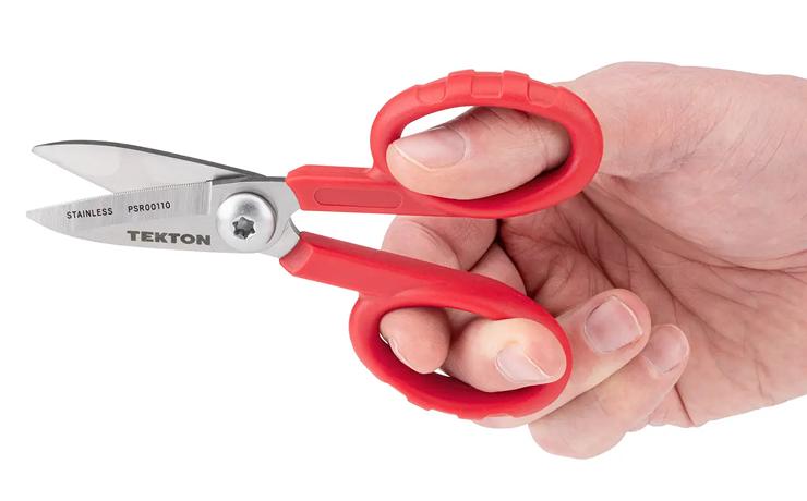 A person holding Tekton's red-handled shop scissors